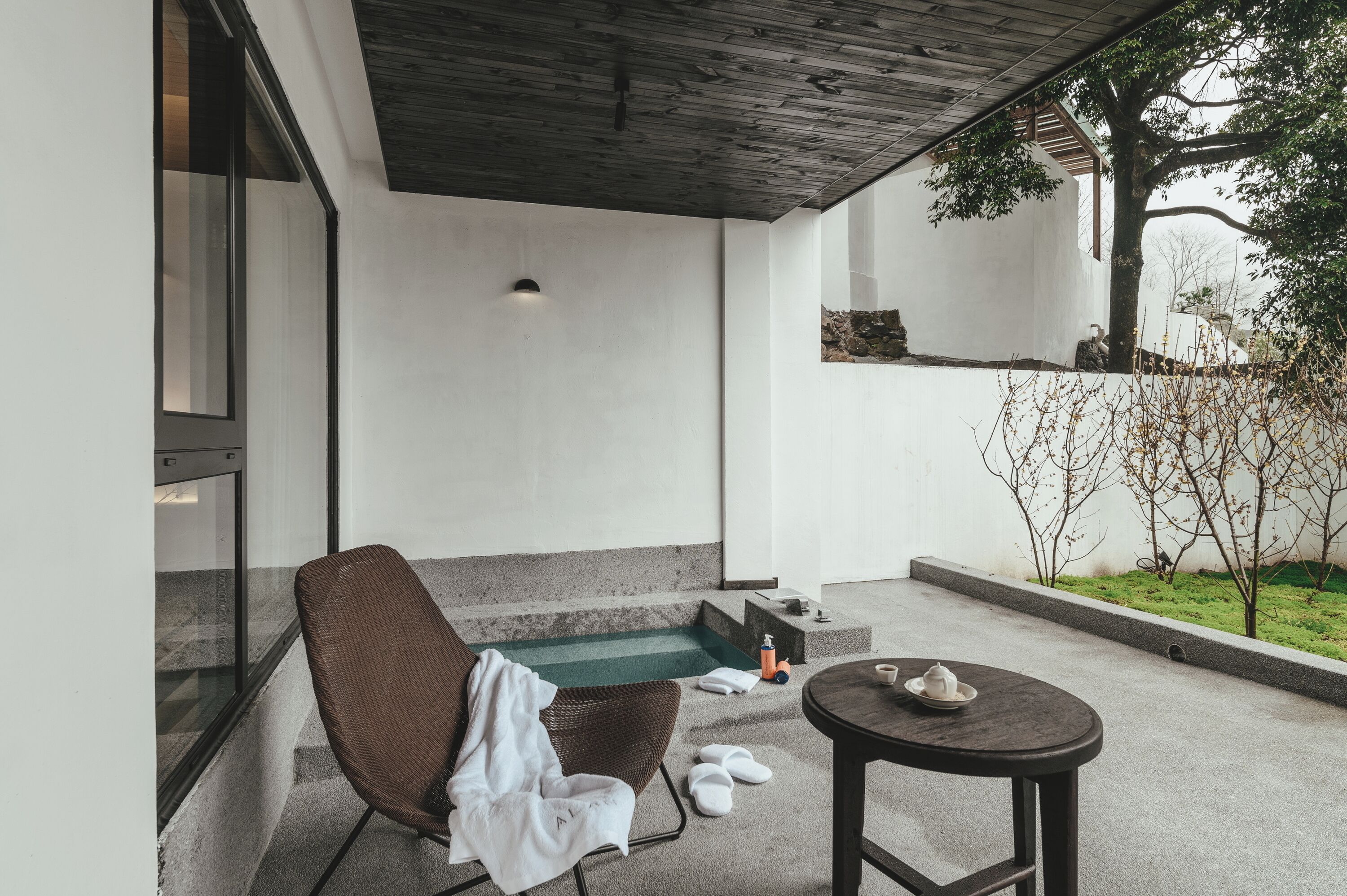 A modern outdoor seating area with a chair, a small table, and a green mat.
