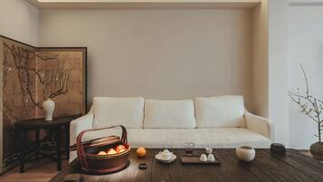 Ein modernes Wohnzimmer mit einem weißen Sofa, einem Holztisch mit Tee-Set und einer dekorativen Vase.