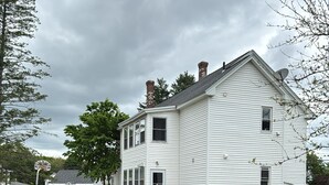 A two-story white house with a front porch, a satellite dish, and a garage. - Heated Winter Stay • 3BR Home • Pet-Friendly • Free Parking • Near Hospitals • 6 (Manchester)