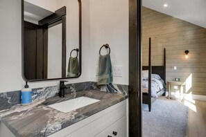 Un bany amb un lavabo de marbre, un mirall gran i un penjallot de tovalloles.
