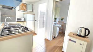 Une cuisine compacte équipée d’une cuisinière à gaz, d’un four à micro-ondes et d’un petit meuble contenant une bouilloire.