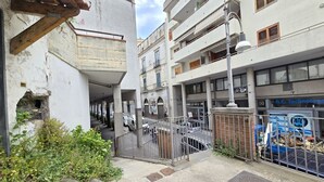 Une ruelle étroite avec un portail en métal, un immeuble doté de balcons et une enseigne indiquant « A.C. Technology ».