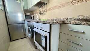A compact kitchen with a stainless steel refrigerator, a washing machine, and a microwave. - Arco Nº 6 - nice studio in first line to the sea (Playa De Los Cristianos)