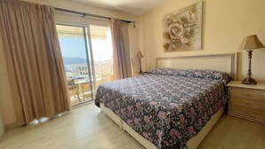 A bedroom with a large bed, a view through a sliding door, a lamp, and a painting on the wall. - Arco Nº 6 - nice studio in first line to the sea (Playa De Los Cristianos)