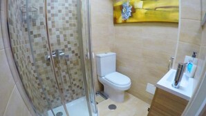 A bathroom with a glass-enclosed shower, a toilet, and a sink with a mirror. - Arco Nº 6 - nice studio in first line to the sea (Playa De Los Cristianos)