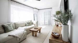 Un salon moderne avec un canapé, une table basse et une grande plante en pot.