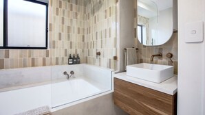Une salle de bain moderne avec une grande baignoire, deux lavabos et un miroir.