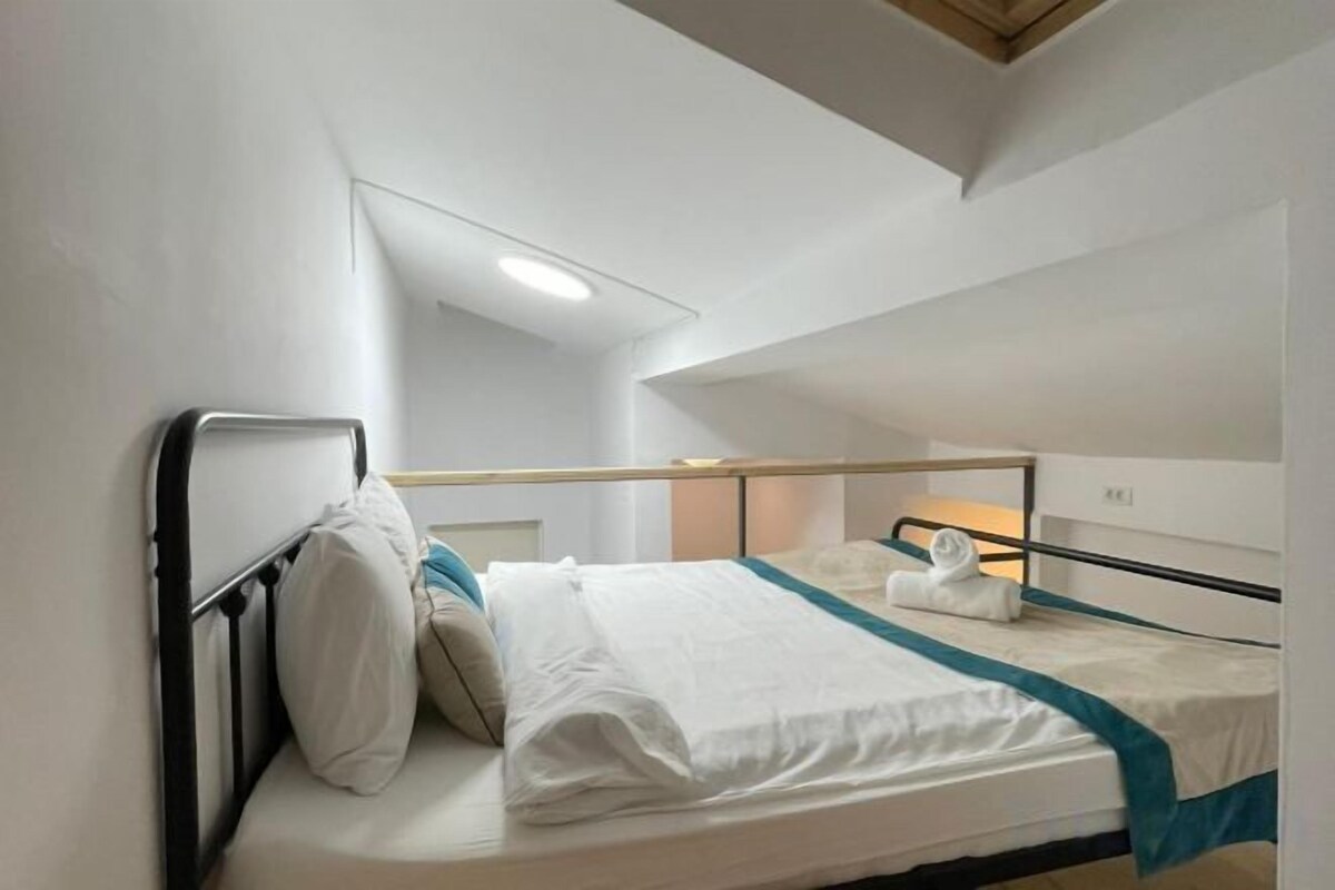 A single bed with a headboard, a bedside table, and a window.