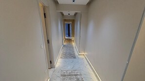 En hall med ett mönstrat mattgolv, marmorgolv och infälld belysning.
