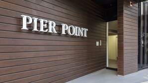 A building entrance with a sign reading "PIER POINT" on a wooden wall. - Oceanfront 2-bed With Balcony & Study Nook (Geelong)