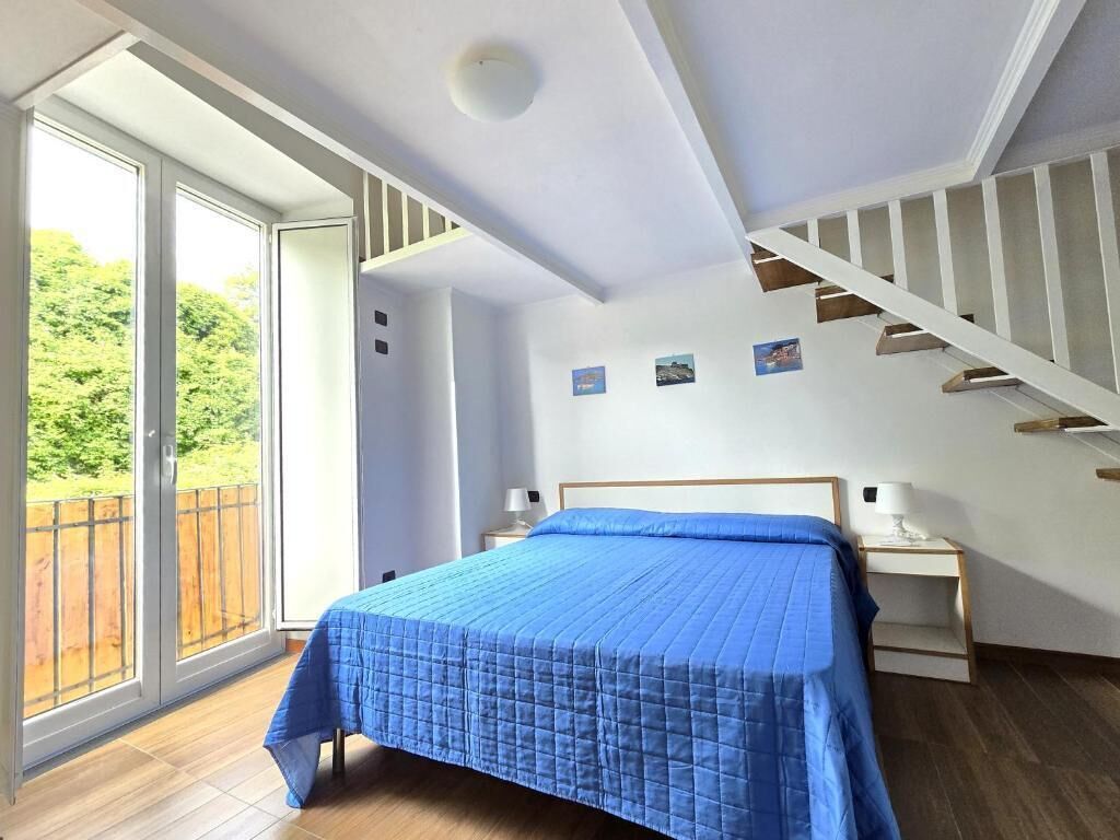 Ein Schlafzimmer mit einem großen Bett, Holzboden, weißer Decke und einer Treppe.