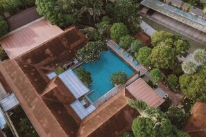 An aerial view of a property with a swimming pool surrounded by trees and a building with a tiled roof. - Villa Wanida Garden Resort (Pattaya)
