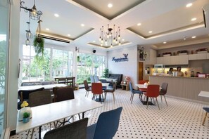 Un espace repas avec une table blanche, des chaises bleues et un sol à motifs.