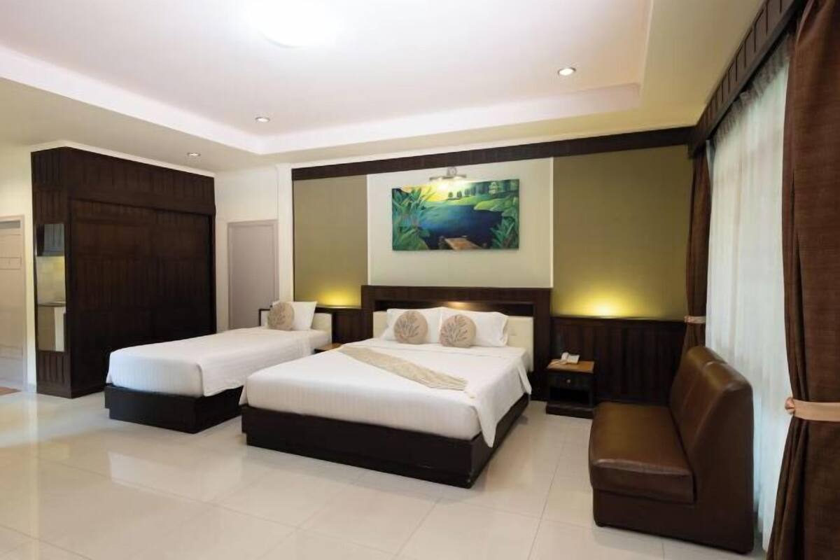 A hotel room with two beds, a sofa, a painting, and a nightstand.