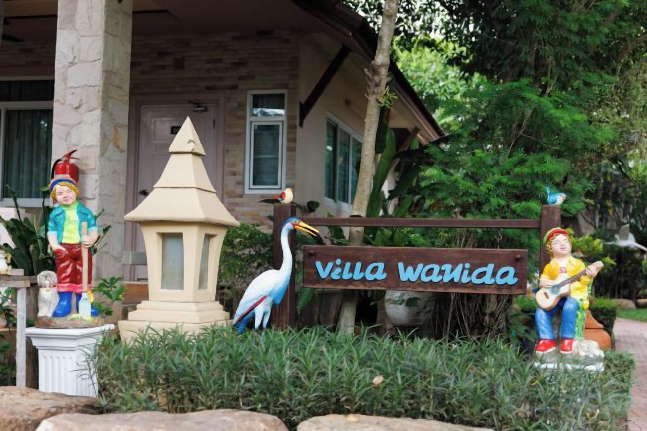 Una vil·la amb un rètol que diu 'Villa Wavida', envoltada d'estàtues i una escultura d'ocell.