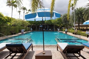 A pool area with lounge chairs and umbrellas. - Villa Wanida Garden Resort (Pattaya)