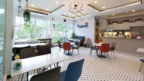 A restaurant with a modern interior, featuring a mix of dining tables and chairs, a bar area, and a visible menu board.
