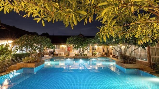 A swimming pool surrounded by trees and a building with lights.