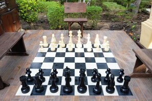 A chessboard set up for a game, surrounded by wooden benches and a rustic outdoor setting. - Villa Wanida Garden Resort (Pattaya)