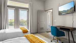 A hotel room with two beds, a desk, a chair, and a TV on the wall. - Charming 2-bedroom apartment with Pool, Gym. Close to Dwtn & Airport (Austin)
