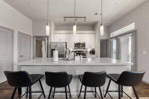 Una cocina moderna con una isla grande, electrodomésticos de acero inoxidable y taburetes negros.