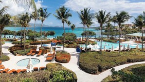 A resort with multiple swimming pools, palm trees, and a view of the ocean.