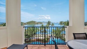 A balcony with a view of a swimming pool and palm trees. - Ritz Carlton Residence spacious 3-bedroom beach front condo with best dates! (St Thomas)