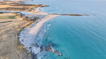 Vue aérienne d’une zone côtière comprenant une plage, un littoral rocheux et des champs agricoles.