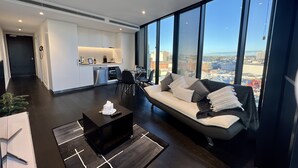 A modern living room with a sofa, coffee table, and dining area. - Stylish 1-bed With Pool, Gym & Free Parking (Brisbane)