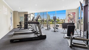Un gimnasio con cintas de correr, máquinas de pesas y un ventanal con vistas a zonas verdes.