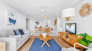 Una sala de estar moderna con sofá, mesa de comedor y televisor.