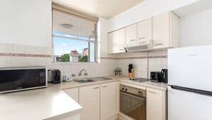 A kitchen with white cabinets, a microwave, a sink, a stove, and a refrigerator. - Bondi Studio Walk to Beach & Cafes (Sydney)