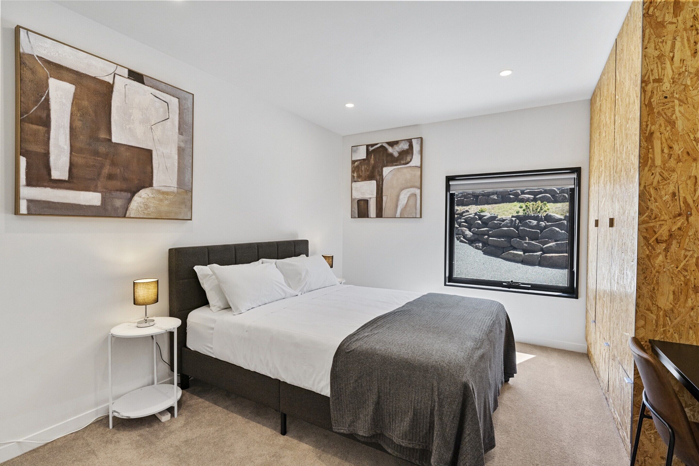 Une chambre à coucher moderne avec un lit, une table de chevet et une grande fenêtre.