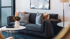 Un salon moderne avec un canapé gris, une table basse ronde et un lampadaire.