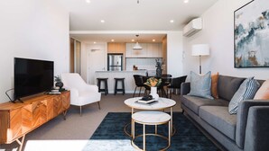 Un salon moderne comprenant un téléviseur, un canapé, une table basse et un coin repas avec des chaises et une table.