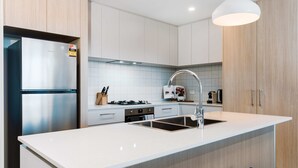 Une cuisine moderne équipée d’un réfrigérateur en acier inoxydable, d’une cuisinière à gaz et d’un évier.