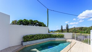 A rectangular swimming pool with a tiled edge, surrounded by a white wall and a white fence. - Oceanside Apartment With Views of Yaroomba Beach (Sunshine Coast)