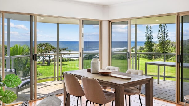 A dining area with a view of the ocean and a lush garden. - Oceanside Apartment With Views of Yaroomba Beach (Sunshine Coast)