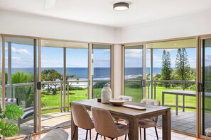 A dining area with a view of the ocean and a lush garden. - Oceanside Apartment With Views of Yaroomba Beach (Sunshine Coast)