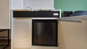 A compact kitchenette with a built-in refrigerator, a microwave, and a small sink.