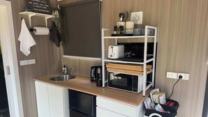 Een kleine keuken met een spoelbak, een broodrooster, een koffiezetapparaat en een magnetron.