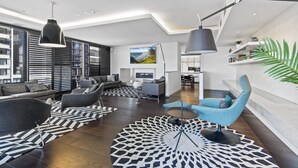 Ein modernes Wohnzimmer mit einer Couch, Sesseln, einem Couchtisch und einem Fernseher.