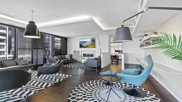 A modern living room with a sofa, armchairs, a coffee table, and a TV.