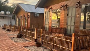 A row of wooden cabins with a brick pathway leading to them.