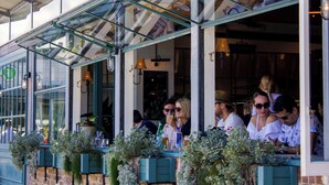 An outdoor seating area with tables and chairs, a glass enclosure, and potted plants. - Manly Muse with Water View and Lock Up Garage (Manly)