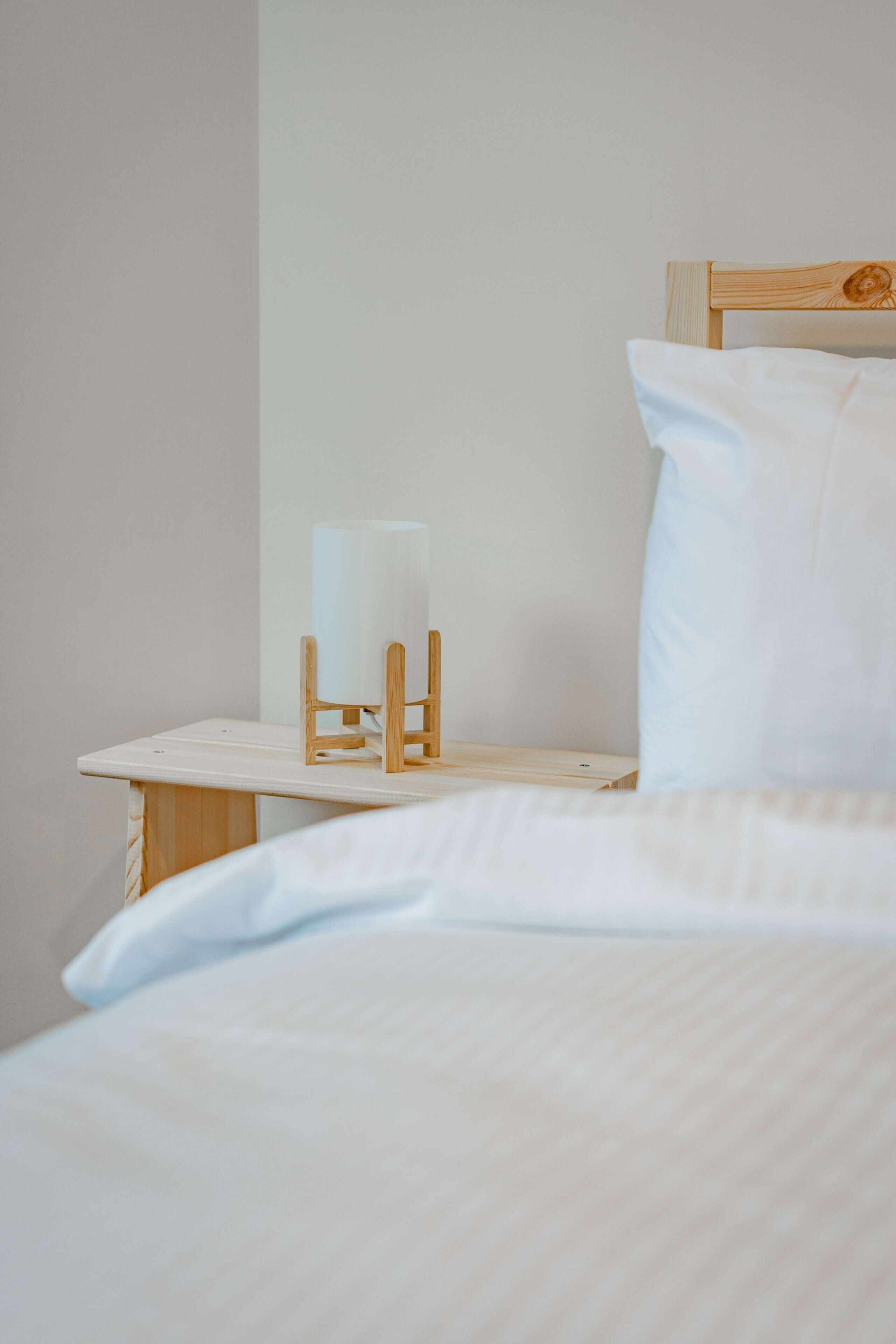 A neatly made bed with white linens and a wooden headboard.