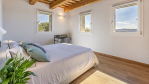 Ein Schlafzimmer mit einem Bett, einem Schreibtisch und zwei Fenstern.