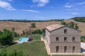 A two-story stone building with a swimming pool and outdoor seating area.