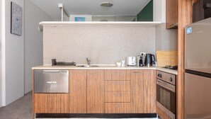 Une cuisine compacte dotée de meubles en bois, d’un lave-vaisselle encastré, d’une cuisinière et d’une machine à café.
