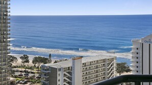 A coastal hotel with a view of the ocean, featuring multiple balconies, a parking area, and a beach in the background. - Ocean View 2-bed Studio In the Heart of Surfers (Gold Coast)